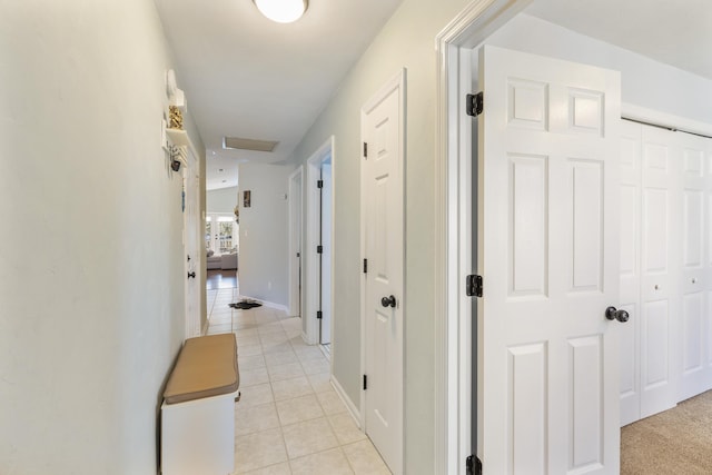 hallway featuring light tile patterned floors and attic access