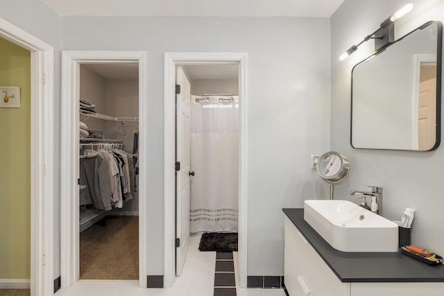 bathroom with curtained shower, a spacious closet, vanity, and tile patterned floors