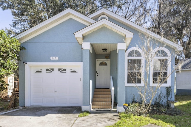 view of front of house with driveway, an attached garage, and stucco siding