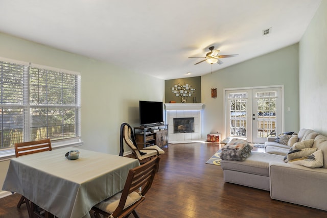 living area featuring lofted ceiling, visible vents, ceiling fan, wood finished floors, and a tile fireplace