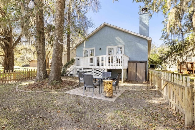 rear view of property with a fenced backyard, a chimney, an outdoor structure, a patio area, and stucco siding