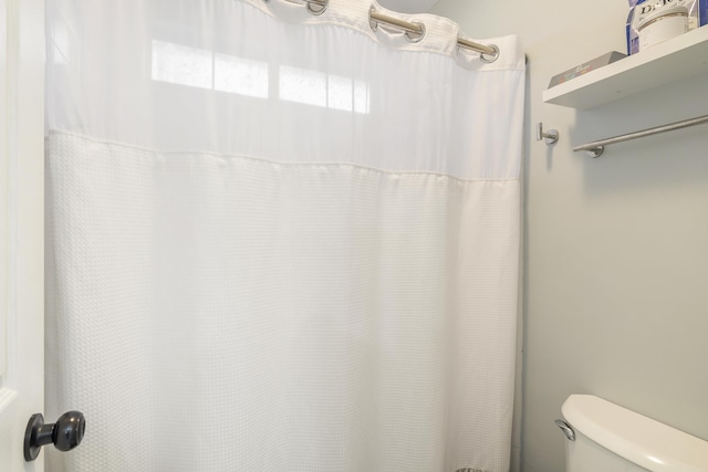 bathroom with toilet and a shower with curtain