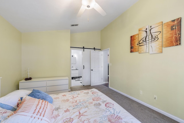 carpeted bedroom featuring visible vents, a barn door, connected bathroom, vaulted ceiling, and baseboards