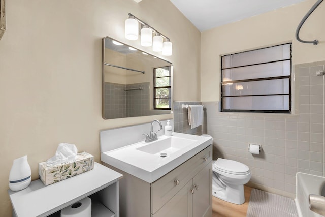 full bathroom with tile walls, toilet, wainscoting, vanity, and shower / tub combination