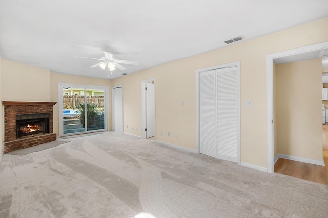 unfurnished living room with carpet, baseboards, a fireplace, and visible vents