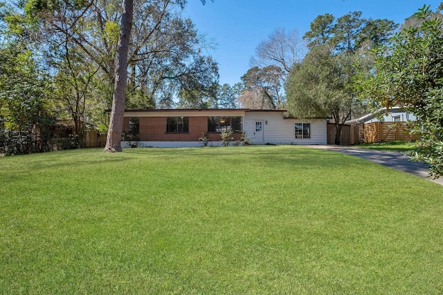 rear view of house with brick siding, a lawn, and fence