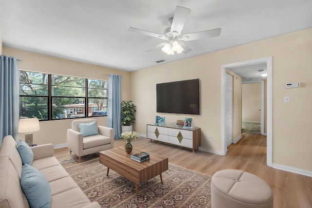 living room featuring ceiling fan, light wood-style flooring, visible vents, and baseboards