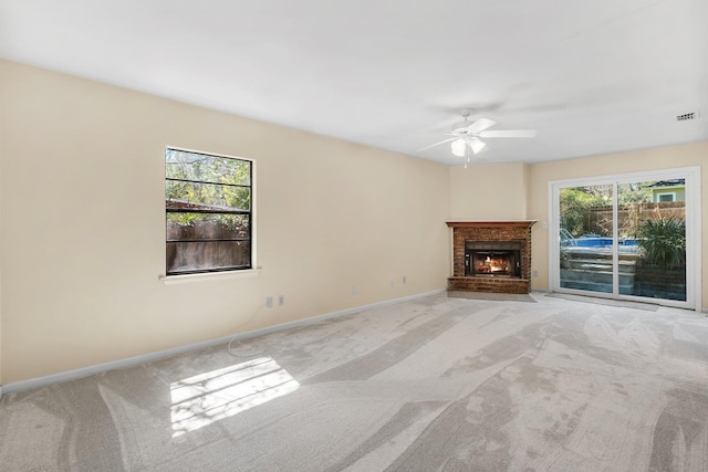 unfurnished living room with carpet floors, plenty of natural light, visible vents, and a brick fireplace