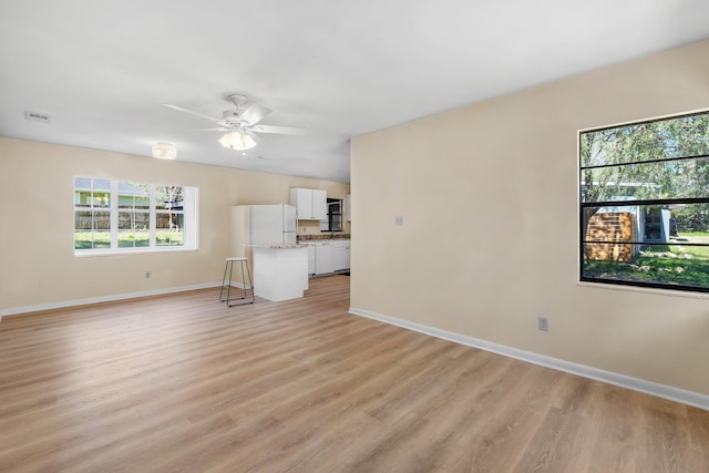 unfurnished living room featuring light wood finished floors, ceiling fan, visible vents, and baseboards