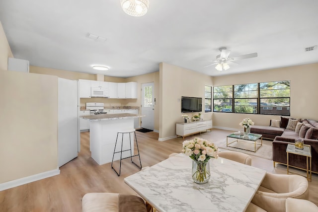 interior space with baseboards, visible vents, ceiling fan, and light wood finished floors