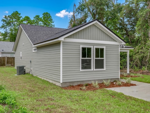 view of side of home with central AC unit and a lawn