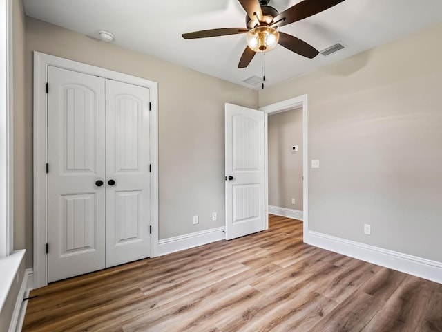 unfurnished bedroom featuring ceiling fan, a closet, and light wood-type flooring