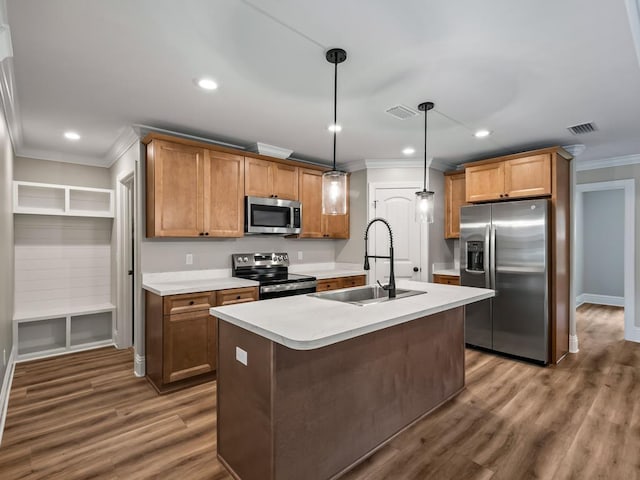 kitchen with a center island with sink, stainless steel appliances, pendant lighting, crown molding, and sink