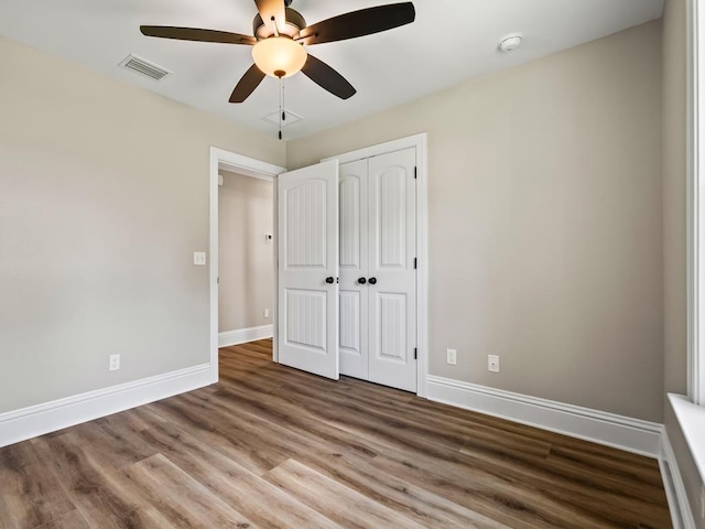 unfurnished bedroom featuring ceiling fan, wood-type flooring, and a closet