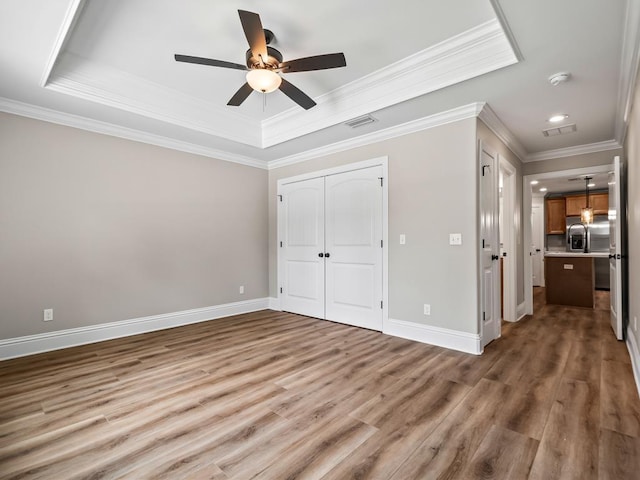 unfurnished bedroom with stainless steel fridge with ice dispenser, hardwood / wood-style floors, ceiling fan, a raised ceiling, and ornamental molding