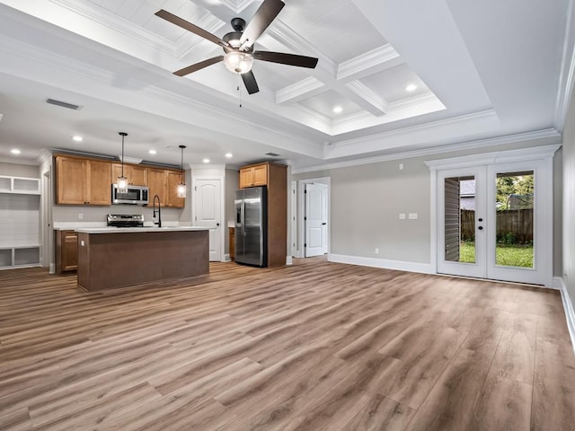 kitchen with stainless steel appliances, french doors, an island with sink, light hardwood / wood-style floors, and hanging light fixtures