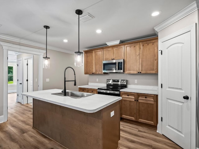 kitchen featuring decorative light fixtures, dark hardwood / wood-style floors, a center island with sink, sink, and appliances with stainless steel finishes