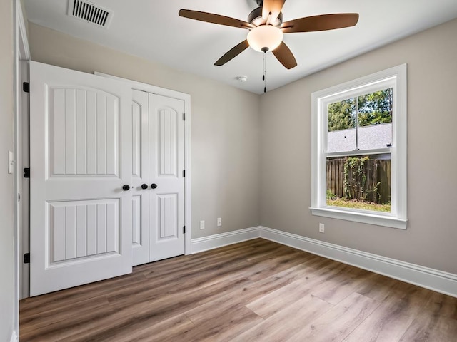 unfurnished bedroom with ceiling fan, a closet, and wood-type flooring