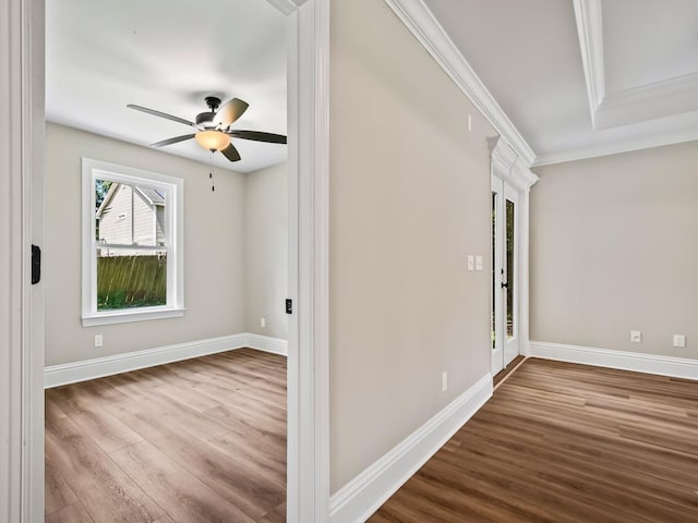 interior space with ceiling fan, a tray ceiling, crown molding, and hardwood / wood-style flooring