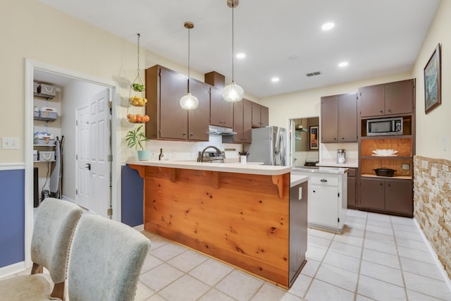 4557 Running Meadows Ln, Tallahassee, FL 32303 - kitchen featuring appliances with stainless steel finishes, under cabinet range hood, a peninsula, light countertops, and a kitchen breakfast bar