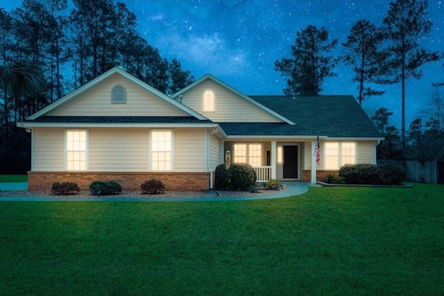 view of front facade featuring a front yard, a porch, fence, and brick siding