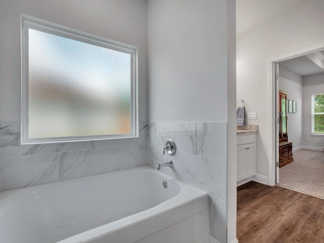 bathroom featuring hardwood / wood-style flooring, vanity, and a tub to relax in