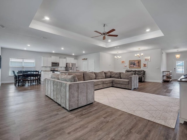 living room featuring a tray ceiling, wood-type flooring, and ceiling fan with notable chandelier