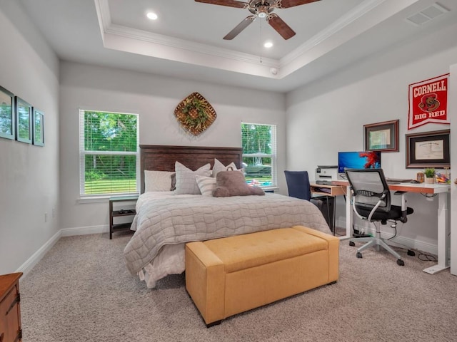 carpeted bedroom with ceiling fan, multiple windows, and a tray ceiling