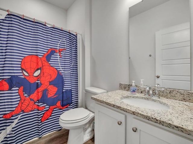 bathroom with a shower with shower curtain, hardwood / wood-style floors, vanity, and toilet