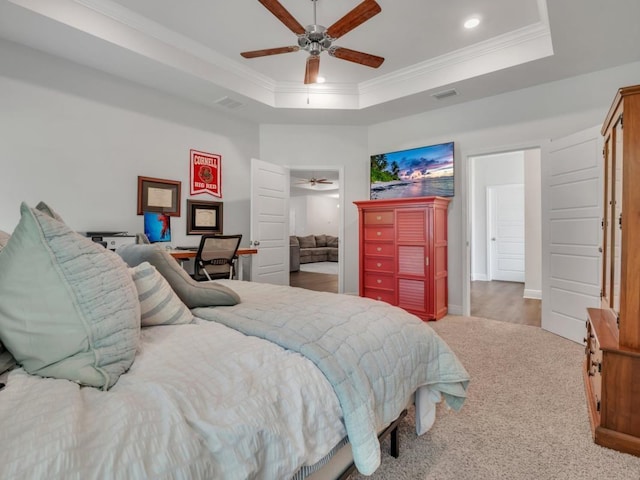 carpeted bedroom with a tray ceiling, ceiling fan, and crown molding