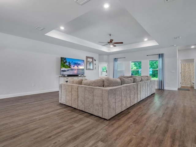 living room with hardwood / wood-style flooring, ceiling fan, ornamental molding, and a tray ceiling