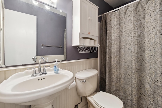 bathroom with wainscoting, a sink, toilet, and a shower with curtain