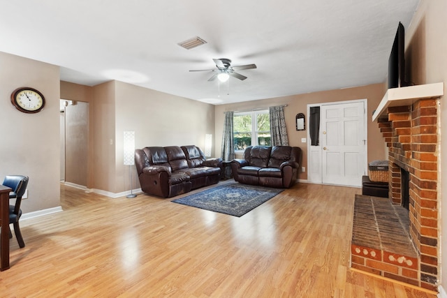 living area featuring light wood-type flooring, baseboards, a fireplace, and visible vents