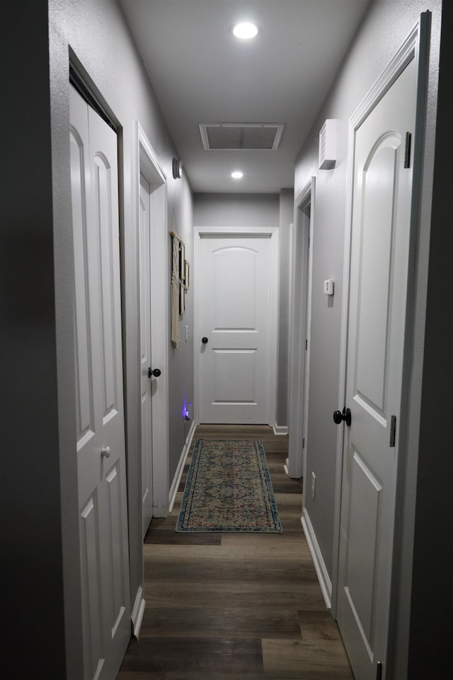 hall featuring dark wood-style floors, visible vents, recessed lighting, and baseboards