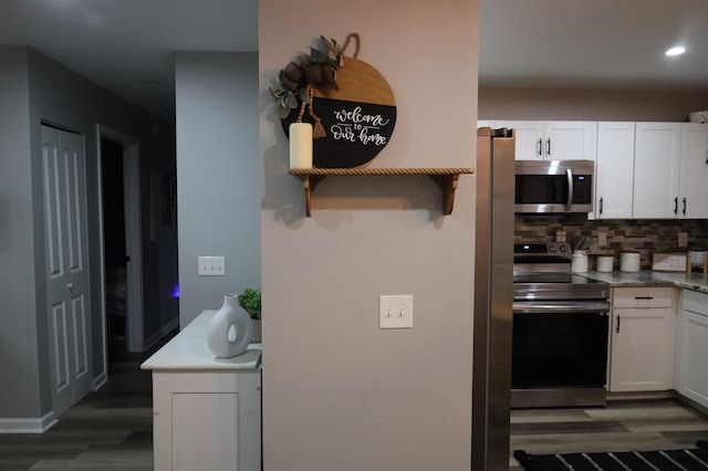 kitchen with white cabinetry, stainless steel appliances, backsplash, and wood finished floors