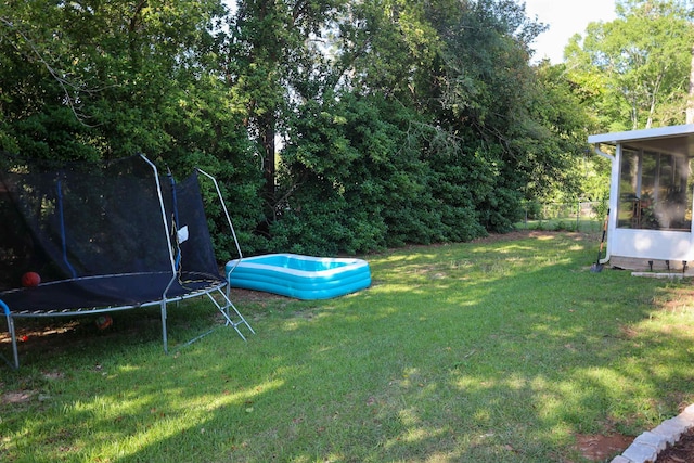 view of yard with a sunroom and a trampoline