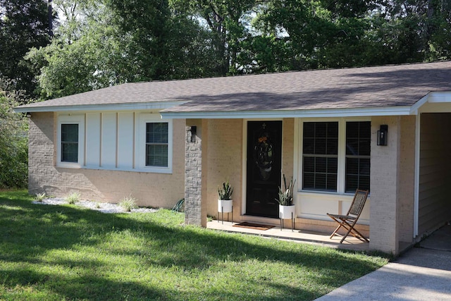 single story home featuring a front yard, roof with shingles, board and batten siding, and brick siding