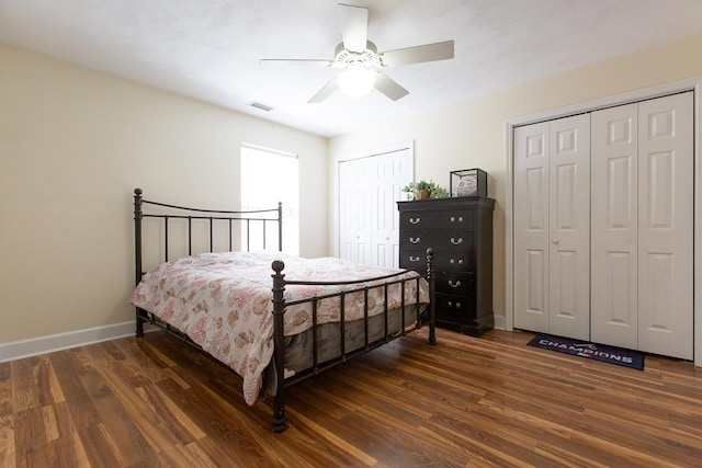 bedroom featuring dark hardwood / wood-style flooring, ceiling fan, and multiple closets