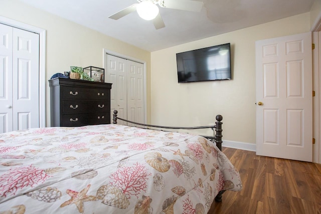 bedroom with ceiling fan, dark hardwood / wood-style flooring, and multiple closets