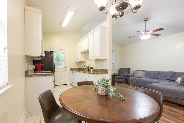 dining room featuring ceiling fan with notable chandelier, sink, light tile patterned flooring, and lofted ceiling