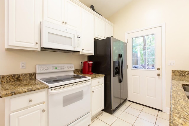 kitchen with white appliances, white cabinetry, dark stone countertops, and light tile patterned flooring