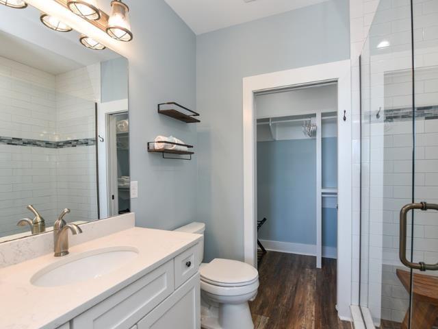 bathroom with toilet, a stall shower, wood finished floors, and vanity