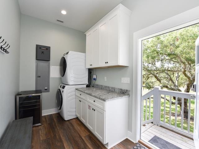 laundry area with cabinet space, baseboards, visible vents, dark wood-style floors, and stacked washing maching and dryer