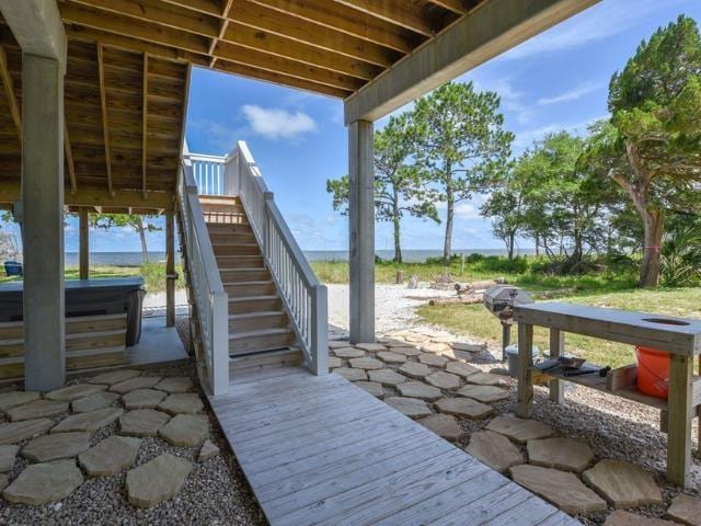 view of patio / terrace with stairway, a water view, and a hot tub