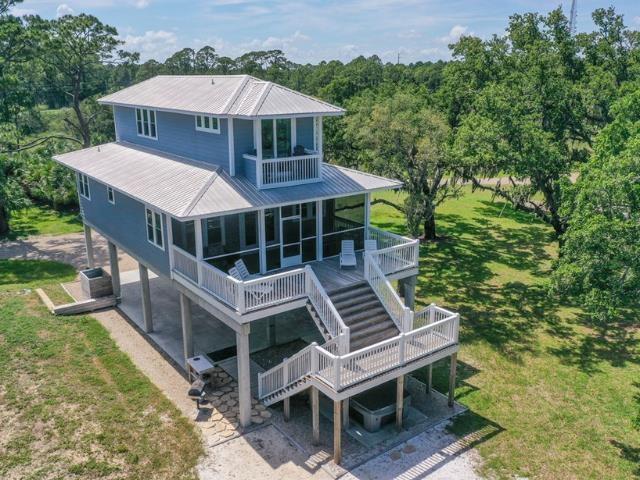 rear view of property with metal roof, stairway, a balcony, and a sunroom