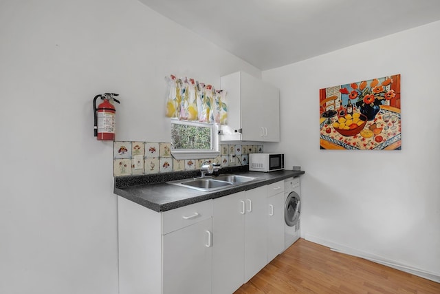 kitchen featuring white cabinetry, sink, washer / dryer, and light wood-type flooring