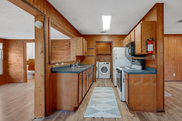 kitchen with white electric stove, sink, wooden walls, and light hardwood / wood-style flooring