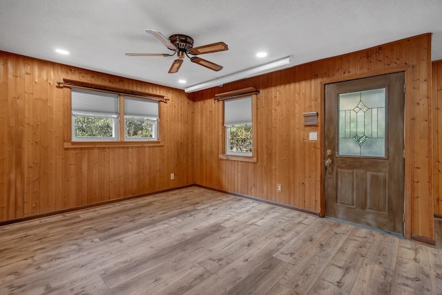 entrance foyer featuring ceiling fan, wooden walls, and light hardwood / wood-style floors