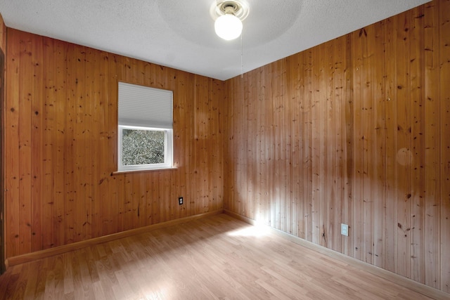 empty room featuring wood-type flooring, wooden walls, and a textured ceiling