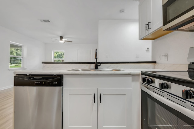 3204 N Ridge Rd, Tallahassee, FL 32305 - kitchen with appliances with stainless steel finishes, light stone counters, ceiling fan, and white cabinets
